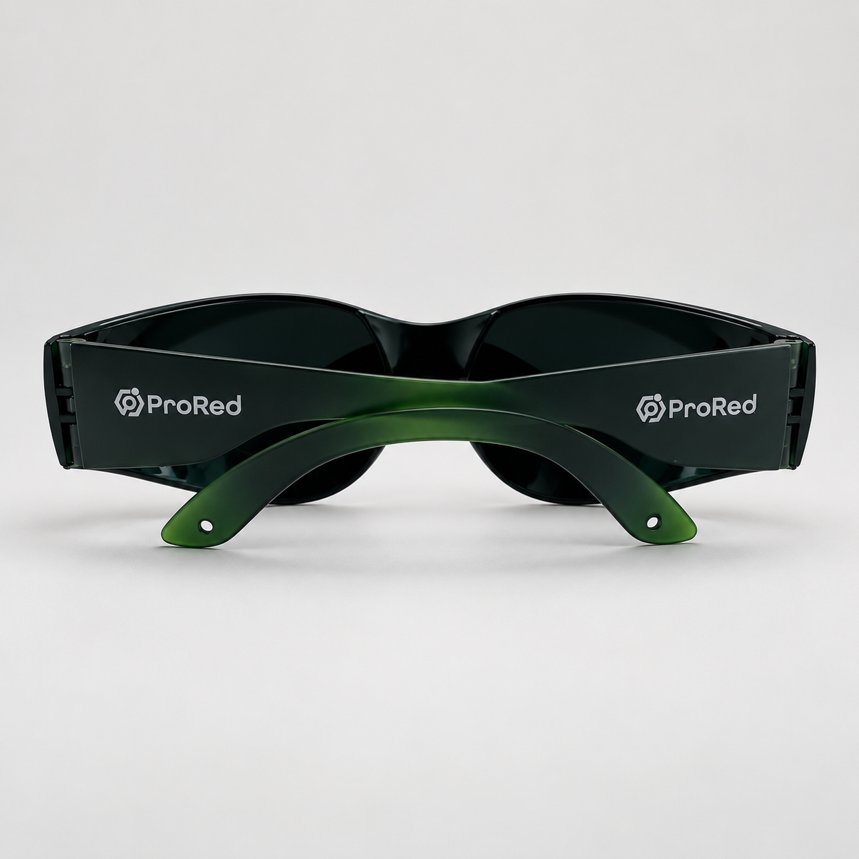A pair of wraparound sunglasses with dark lenses and a translucent green temple arm, featuring the white ProRed logo on both sides, set against a light gray background.
