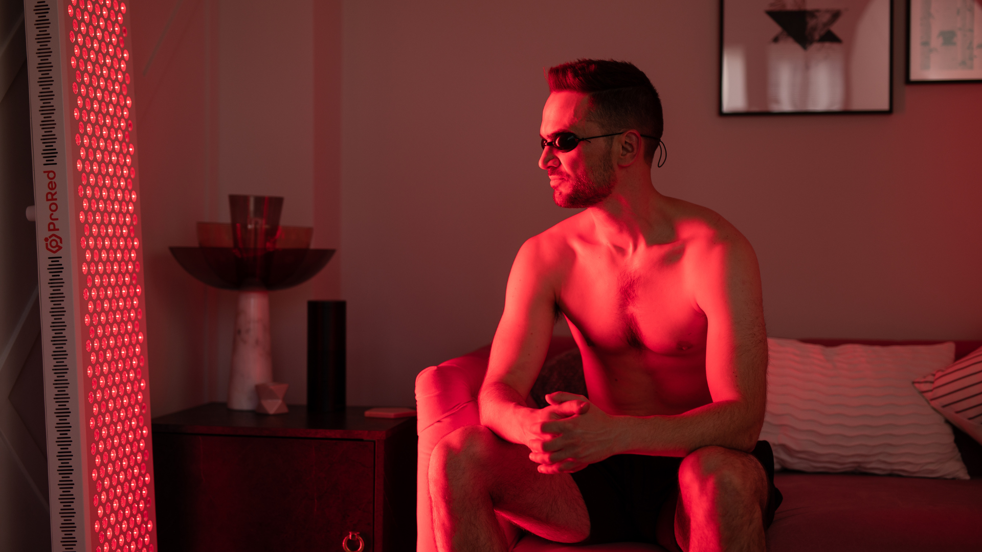 man sat on sofa doing red light therapy